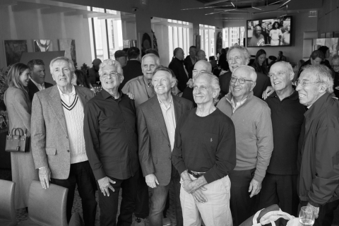 A group of mal alumni gather together and smile in this black-and-white photograph.