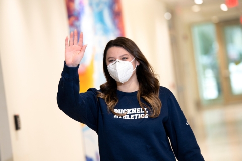 Student wearing a mask waving. 