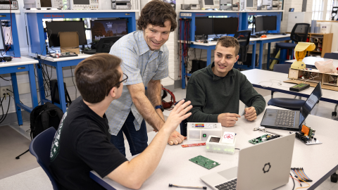 Students at desk with laptops talking