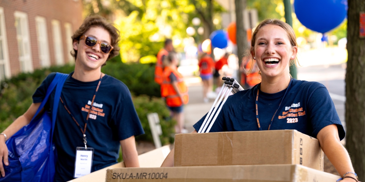 Two students carry boxes for class of 2027 student outside Smith Hall on Move-in Day