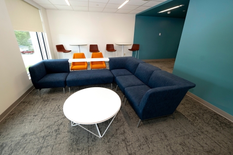 Lounge with blue sectional couch and two-person tables behind