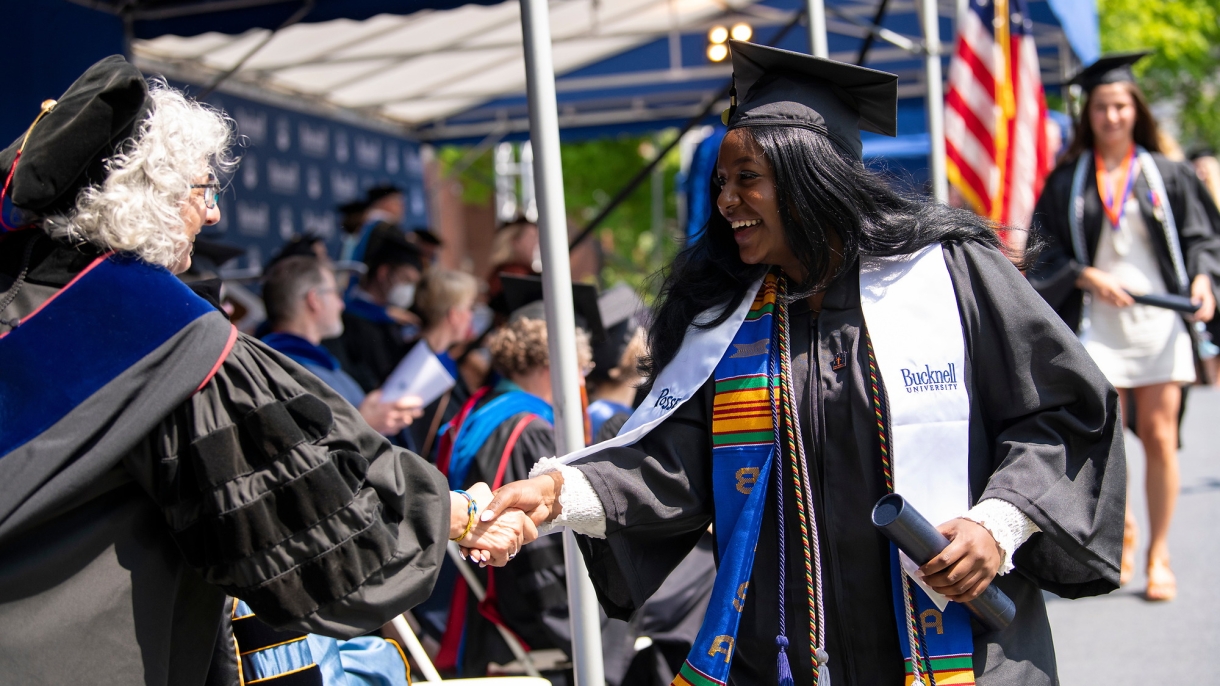 Graduating student shaking hands after receiving diploma.