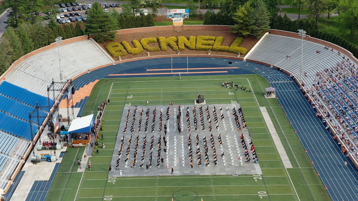 An aerial view of Christy Mathewson-Memorial Stadium during Commencement 2021. Graduates sit on the field in chairs facing a stage.
