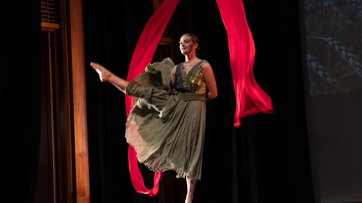 A female dancer with a red ribbon on stage 
