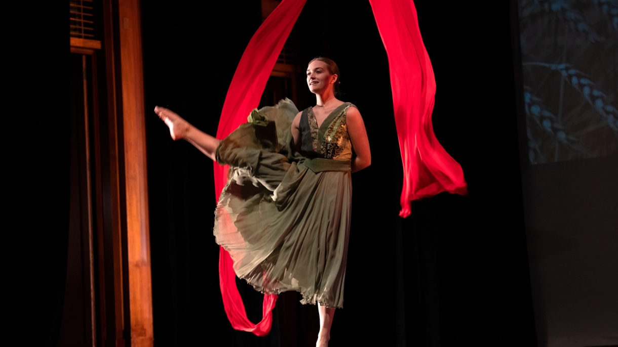 A female dancer with a red ribbon on stage 