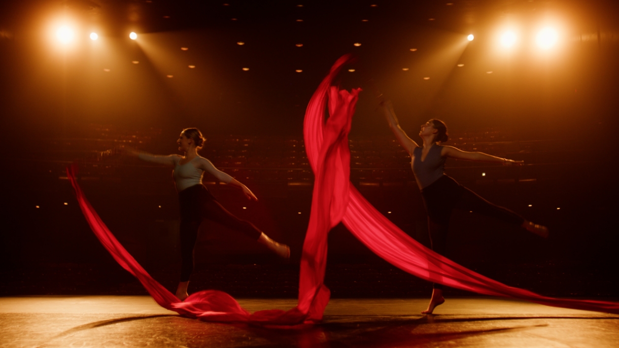 Dancers wave red ribbon on stage