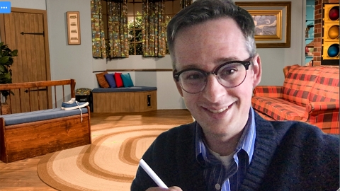 Evan Peck in a Zoom meeting with the Mr. Rogers&#039; Neighborhood home background behind him.