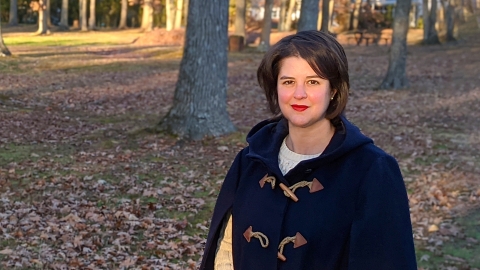 Casey Barber poses before a field of trees and fallen leaves.