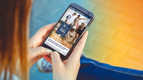 A hand holds a smartphone with a Bucknell Custom Viewbook on the screen