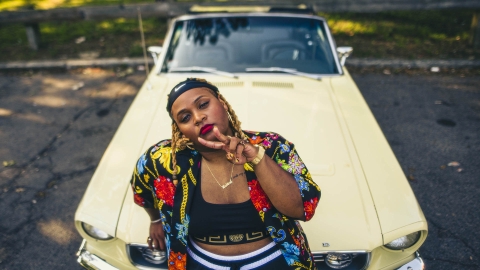 Oompa Williams &#039;14 leans on the hood of a yellow mustang showing a peace sign.