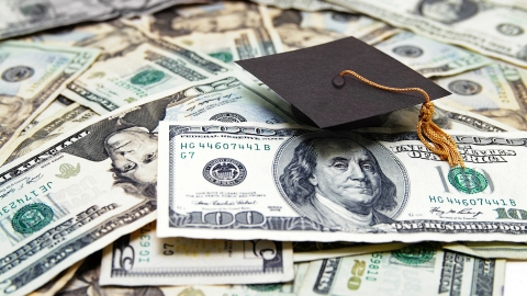 Money laid out with a graduation cap on top.