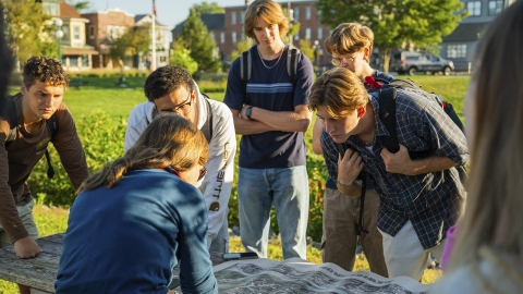 Students outside looking down at a map