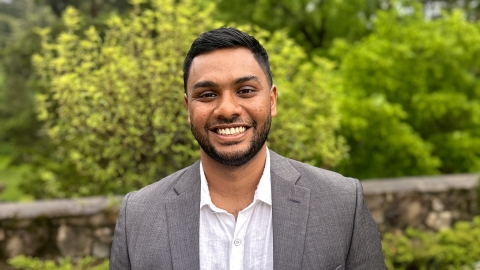 Portrait of Uttam Kumaran wearing a gray suit in a garden