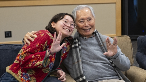 George Takei sitting with student