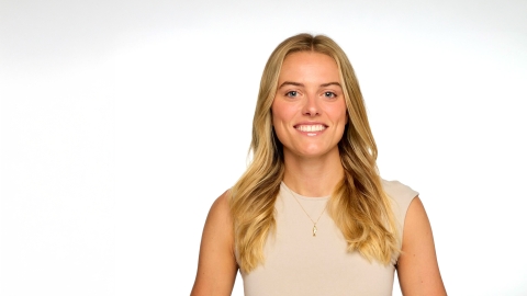Cricket Treanor '18 smiles while wearing a beige sleeveless top against a white background.