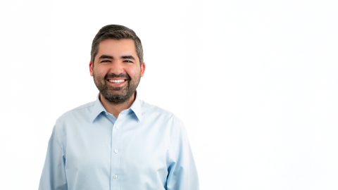 Michel Ajjan wears a white button-down collared shirt and smiles.