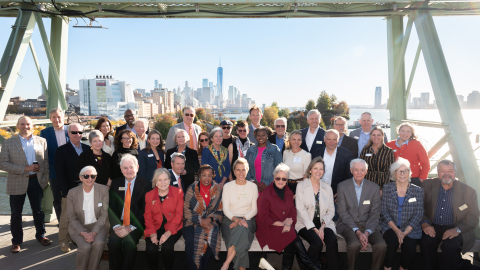 A large group of people pose in front of the New York City skyline.