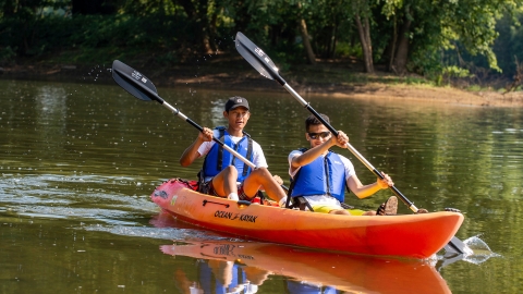 Male students row in an orange kayak on the Susquehanna River