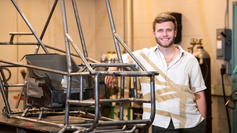 Elliot Thorp &#039;23 stands with a steel frame of a go-kart.