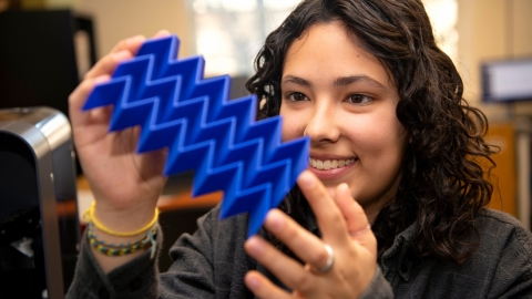 Iona Pitkin '25 looks at a plastic plate with 3D zig-zag design.