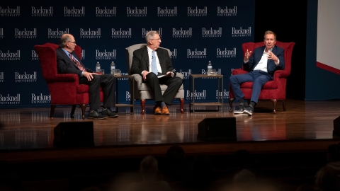 President John Bravman sits between David Axelrod on the left and John Kasich on the right, as Kasich makes a point with his hands.