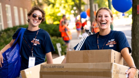 Two students carry boxes for class of 2027 student outside Smith Hall on Move-in Day