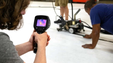 Close up of a student using an infrared camera to collect heat data from a mat welder