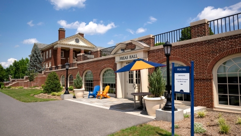 A pair of blue and orange adirondack chairs sit near the entrance of Freas Hall.