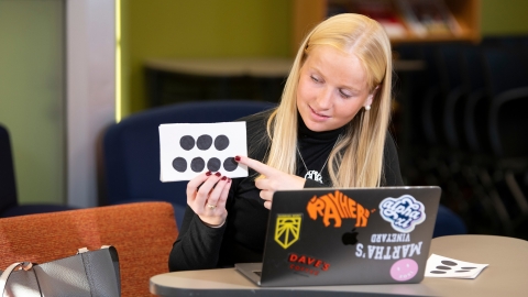 Cara O'Neill points to a flashcard while tutoring elementary school students online