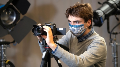Student with camera in media studio
