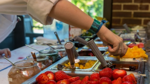 Dining services worker scooping food.