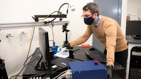 Ben Wheatley leans over a piece of testing equipment next to a computer screen