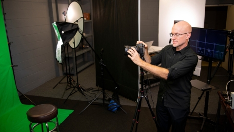 Mark Burke examines a camera while inside a studio.