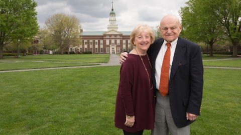 Doris and Bob Malesardi stand on Malesardi Quad with Bertrand Library behind them.