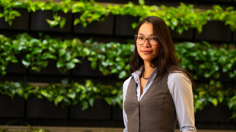 Christine Ngo stands in front of a green, leafy background.