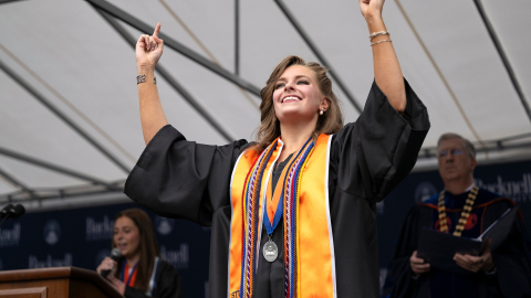 Katie Fitzgerald performs American Sign Language while wearing graduation robes