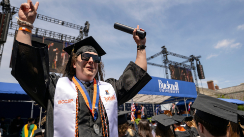 A graduate holds up his degree as he exits the Commencement stage at Bucknell's 2026 Commencement ceremony.