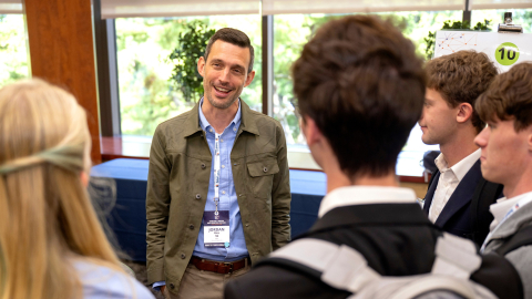 Jordan Rice smiles while talking with a small group of students gathered around him at EC⁴.