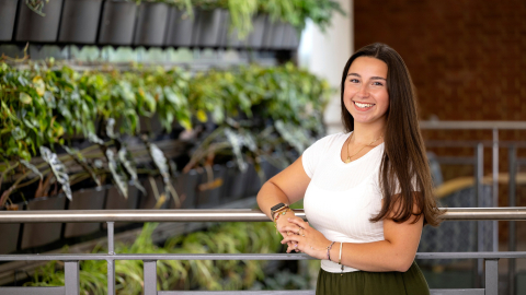 Gianna Sangillo wears a white shirt in front of a green background