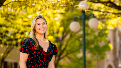 Margo Bigue smiles on campus with bright yellow foliage and a Lewisburg lightpost behind her.