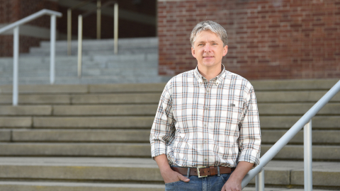 Professor Will Kerber poses on the steps of the Rooke Science Building