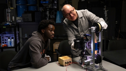John Ogunwomoju '27 and Professor Eric Faden smile as they work using a film projector