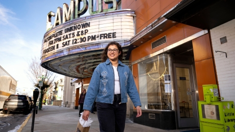 Waina Ali '26 walks down the sidewalk in downtown Lewisburg with the Campus Theatre marquee behind her.