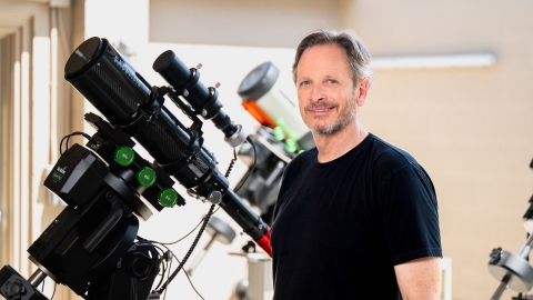 Jack Gallimore stands next to a telescope 