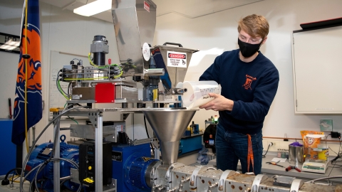 Philip Onffroy pours plastic beads into a hopper.