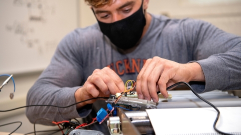 Michael Bortolot connects wires on the sushi sanitizing device