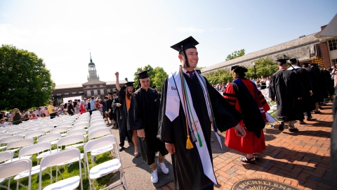 Graduates in cap and gown process into Commencement