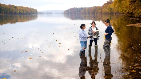 Egineering professor with two students testing water in the Susquehanna River