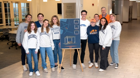 Class of 2022 officers stand with President Bravman alongside an illustration of their class tribute.