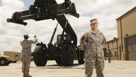 Military woman poses in front of large machinery